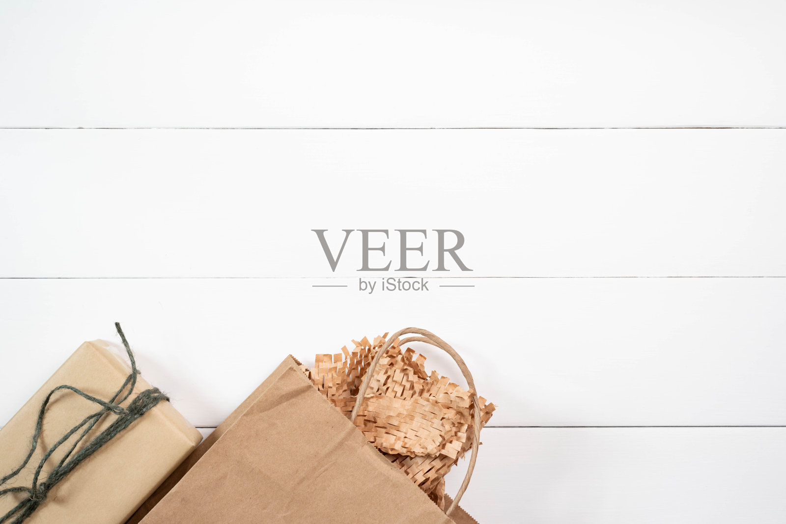 赠送或绿色星期五的概念，礼品包装在普通棕色重新利用纸与绿色黄麻线和纸袋在白色木板背景。照片摄影图片