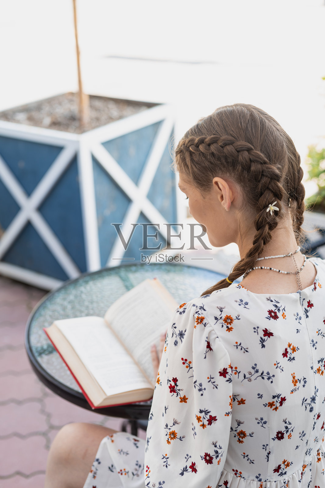 穿着便服的年轻白人女孩，在街边的咖啡馆里看书照片摄影图片