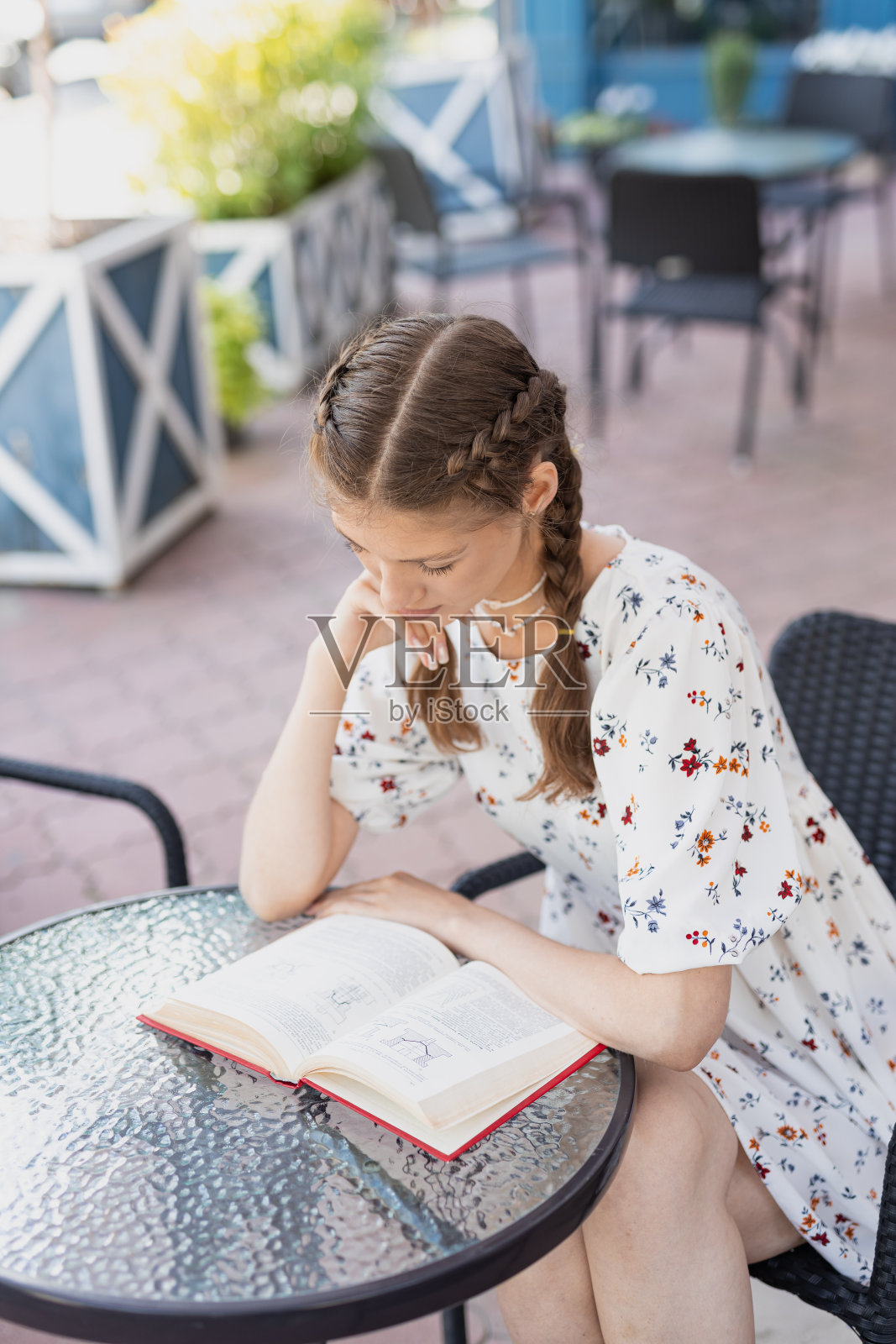 美丽的年轻女子在街上看书，夏日的夕阳照片摄影图片