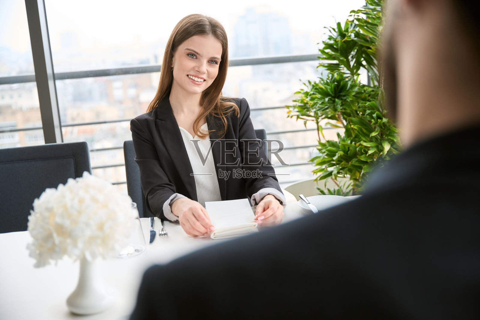 微笑的漂亮女人坐在餐厅看着男人。爱情故事，约会照片摄影图片