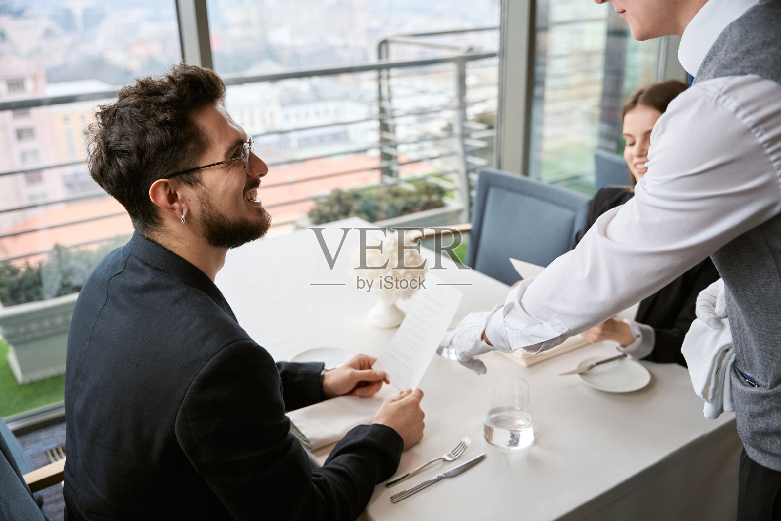 快乐的大胡子男人和他的女朋友坐在餐厅里点餐照片摄影图片