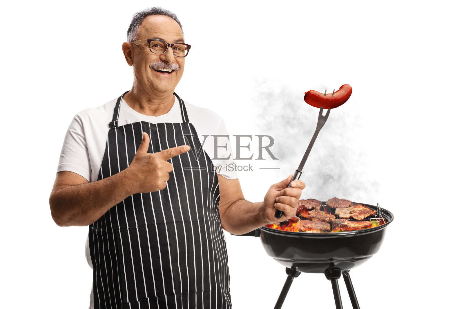 快乐的中年男人在烧烤架前用叉子叉着香肠照片摄影图片