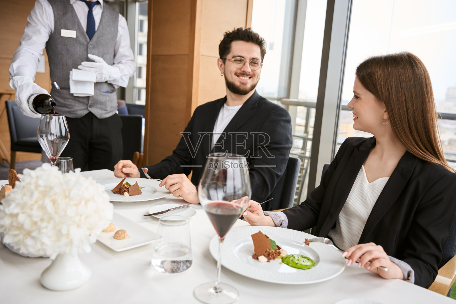 男女在餐厅里看着服务员斟酒照片摄影图片