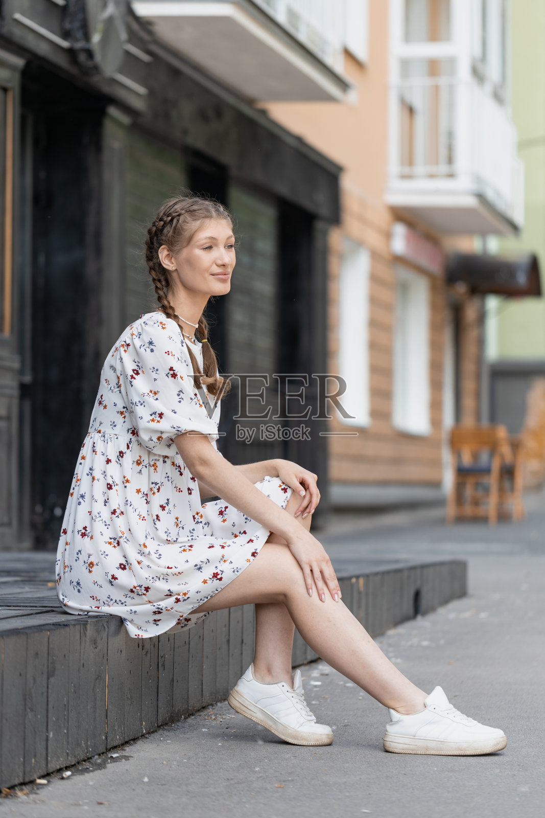 一个年轻的女孩坐在城市街道的拐角处照片摄影图片