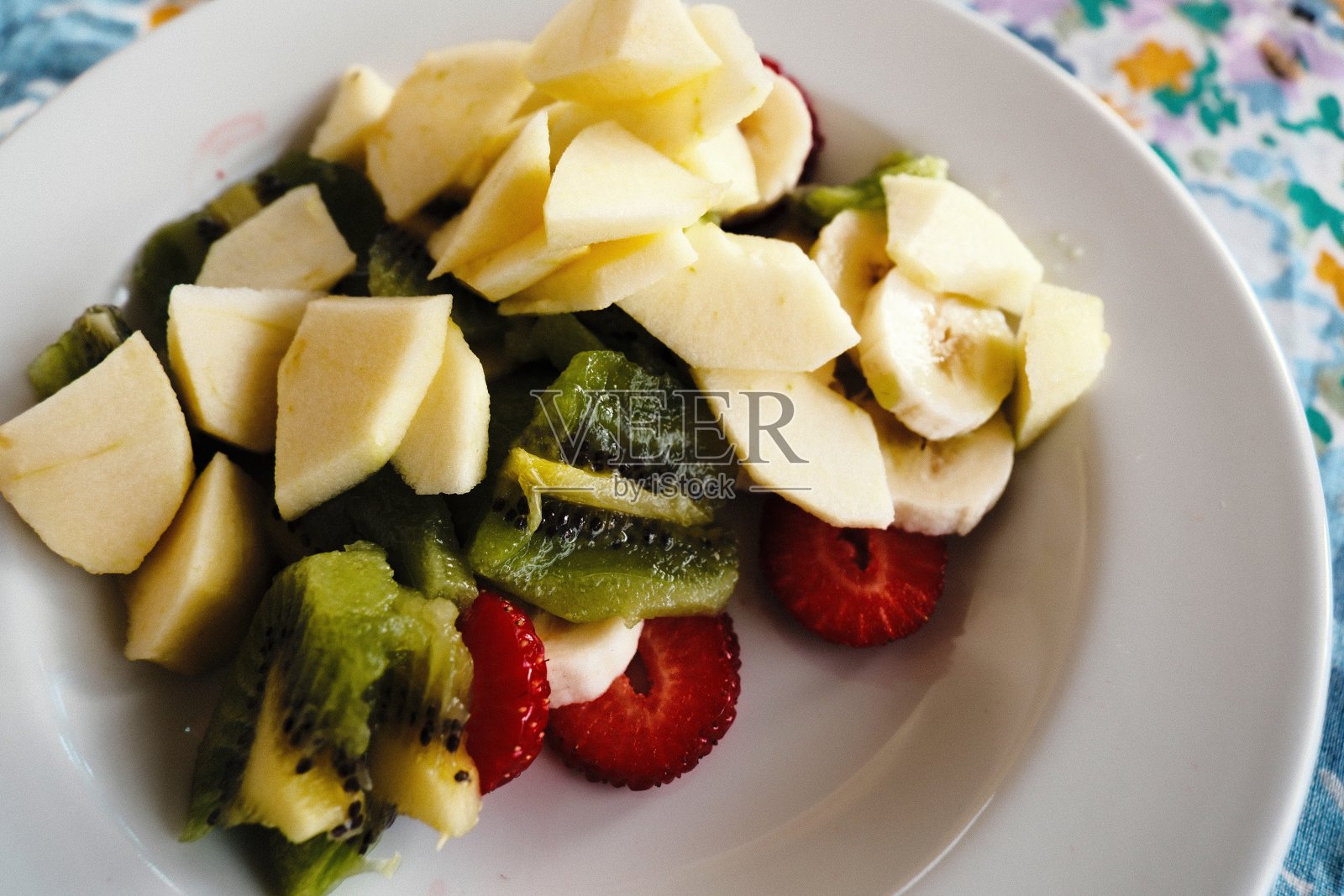 白色的盘子里有新鲜的时令水果。水果沙拉照片摄影图片