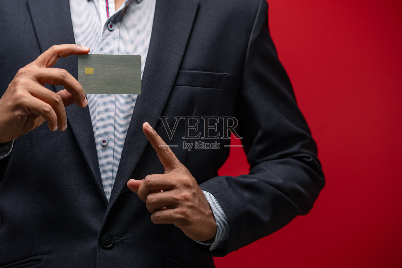 特写手持信用卡的商人的手孤立的红色背景。照片摄影图片