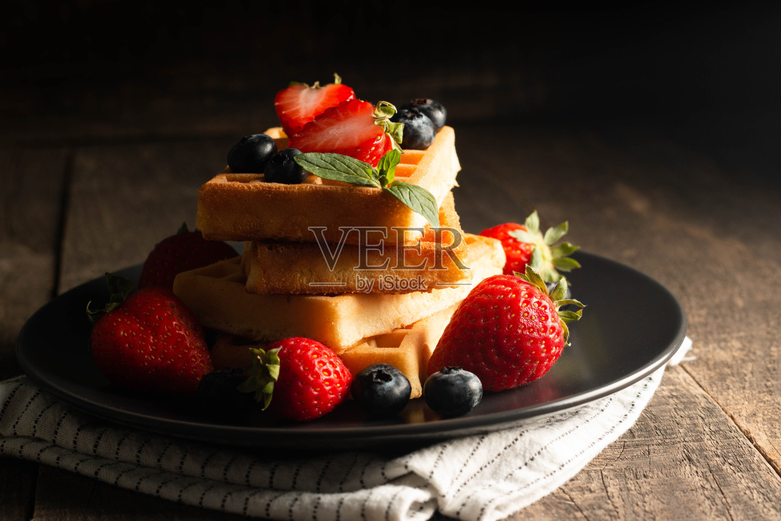 新鲜自制的比利时浆果华夫饼，配以蜂蜜、巧克力、草莓、蓝莓、枫糖浆和奶油。健康甜点早餐搭配咖啡的概念照片摄影图片