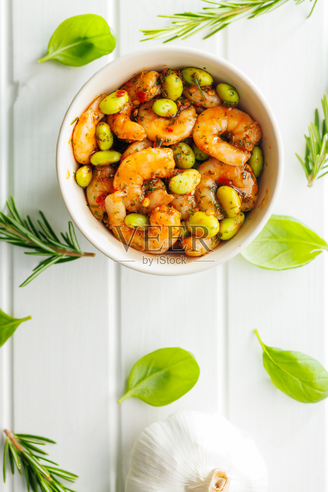 新鲜沙拉，虾和毛豆大豆在碗里在白色的桌子上。照片摄影图片