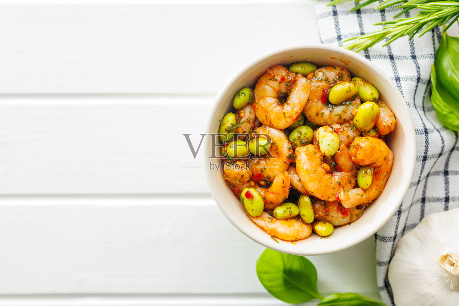 新鲜沙拉，虾和毛豆大豆在碗里在白色的桌子上。照片摄影图片