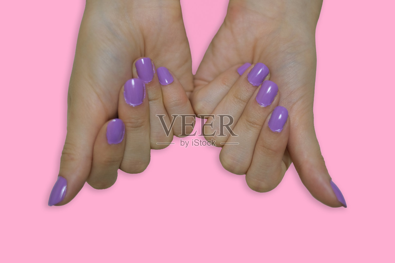 涂指甲油的特写。一个女人用紫色的指甲油涂指甲。照片摄影图片