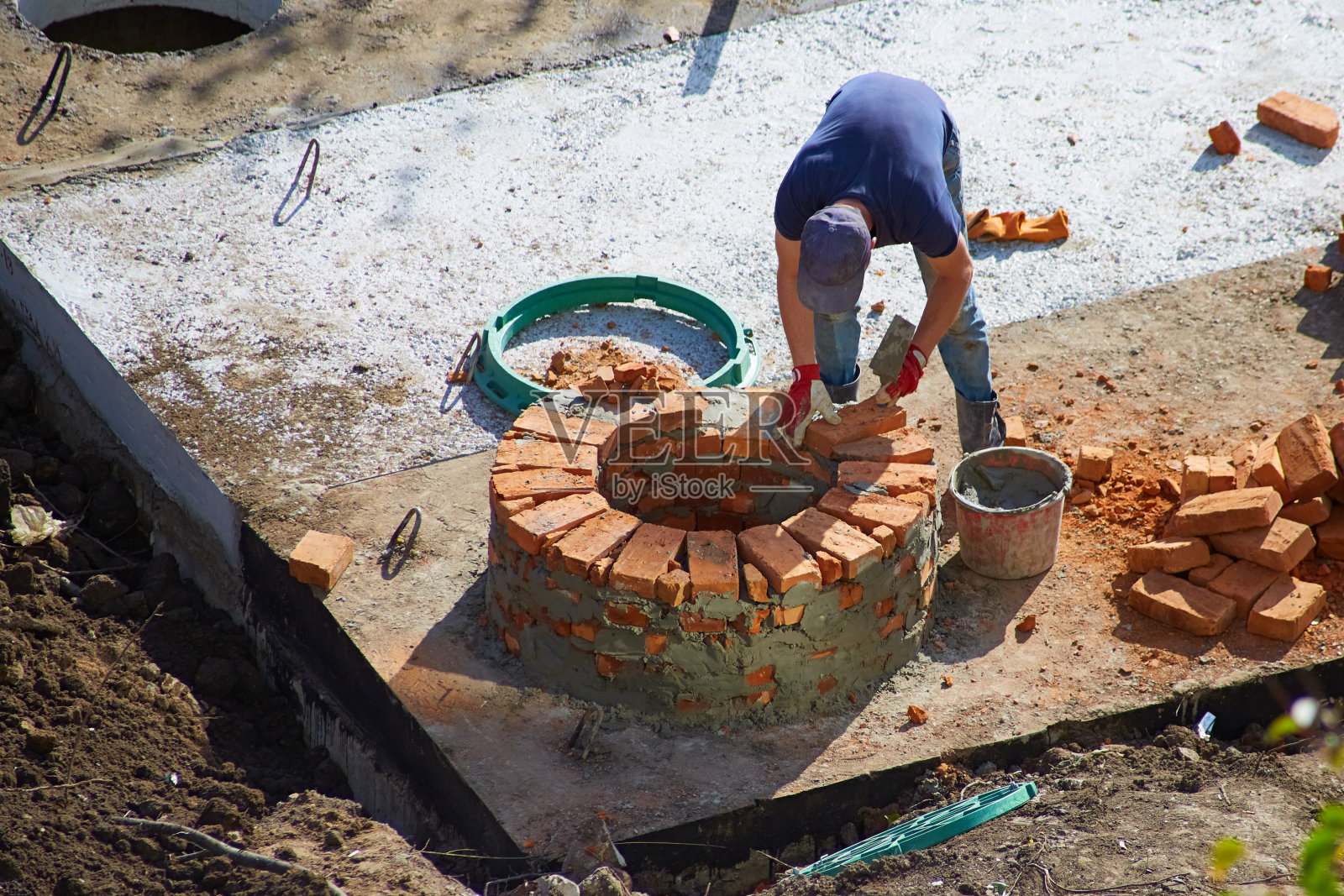 一个工人用砖块砌了一口污水井，一个建筑商用砖块建了一栋房子，建造污水处理设施照片摄影图片