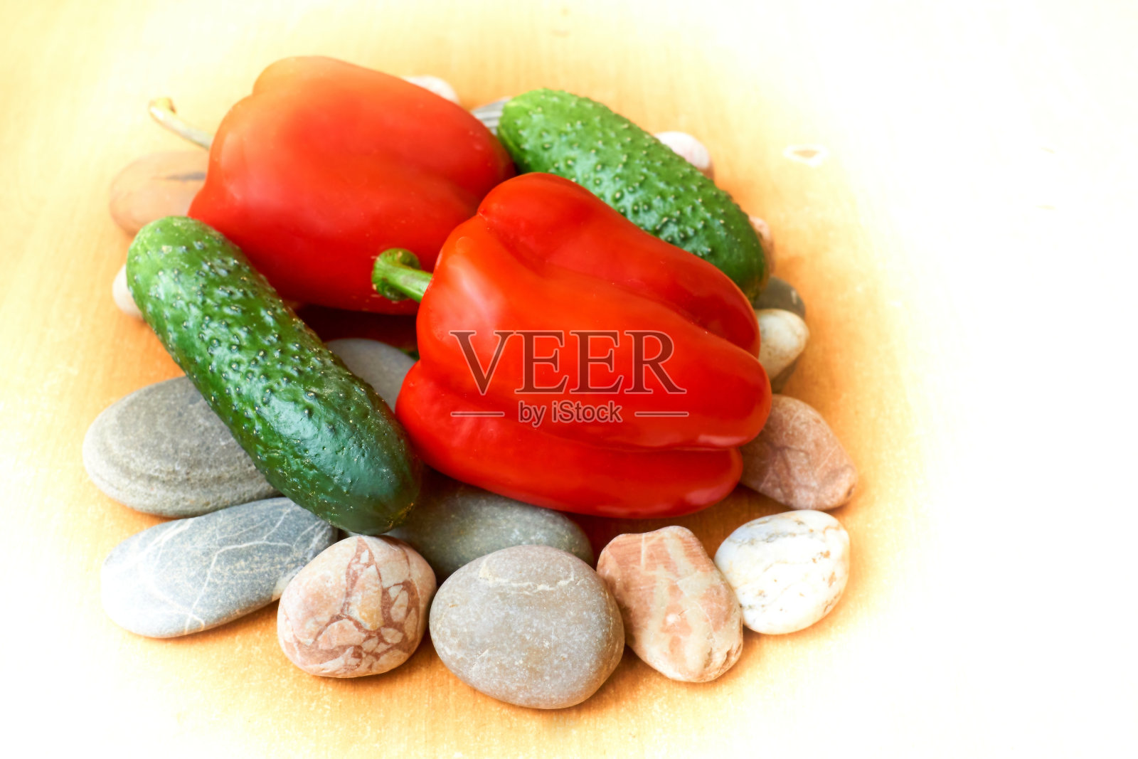 两个红红的甜椒，两个绿黄瓜放在石头上照片摄影图片