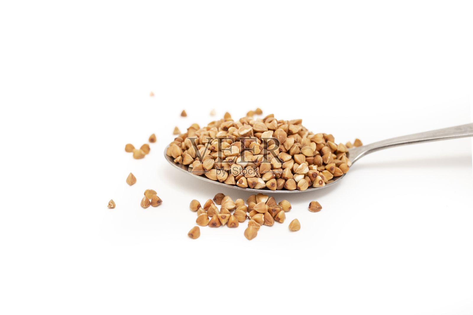 荞麦种子堆在不锈钢勺隔离在白色背景照片摄影图片