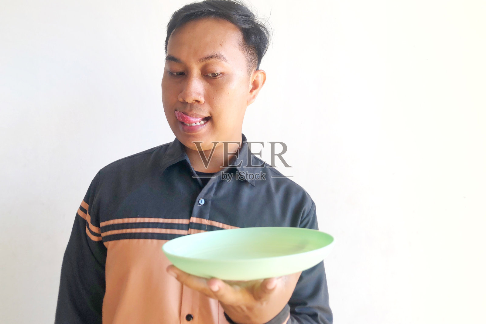 亚洲男人想用滑稽的表情倒空碗里的食物照片摄影图片