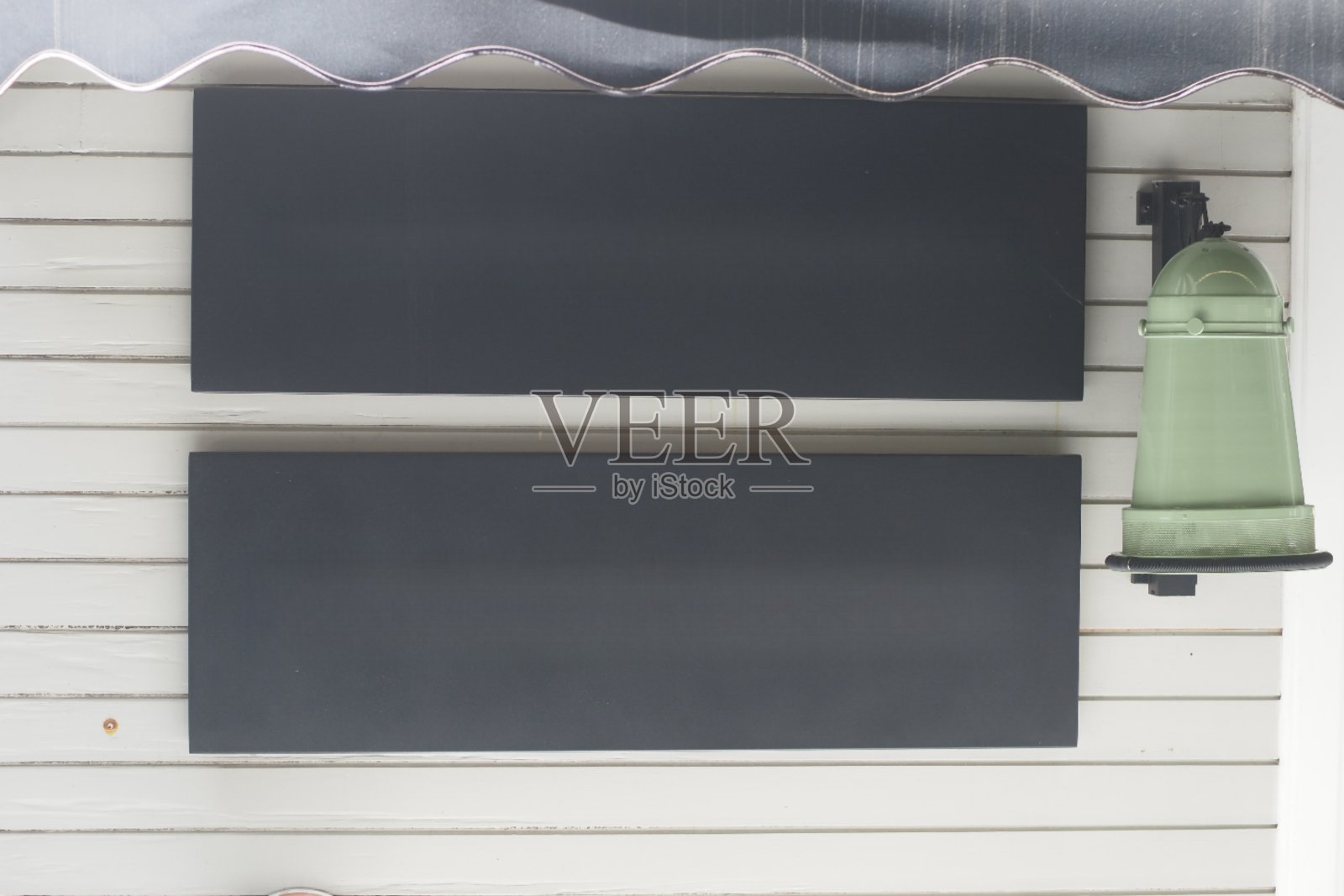 白色墙边的墙上挂着绿色的钟和招牌，展示着建筑和招牌照片摄影图片