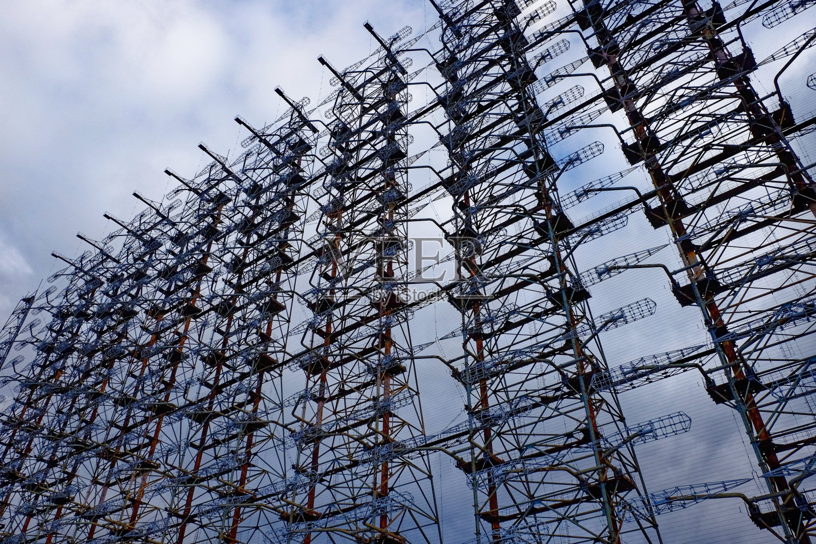 一个由生锈的金属和电线组成的复杂结构，映衬着多云的天空。Duga是苏联的超视距雷达站，用于洲际弹道导弹发射的早期探测系统。照片摄影图片