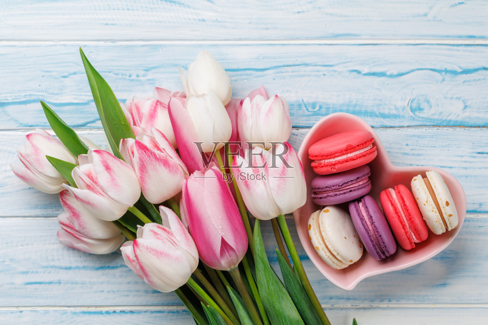 五颜六色的郁金香和充满活力的马卡龙装满了一个心形的碗照片摄影图片