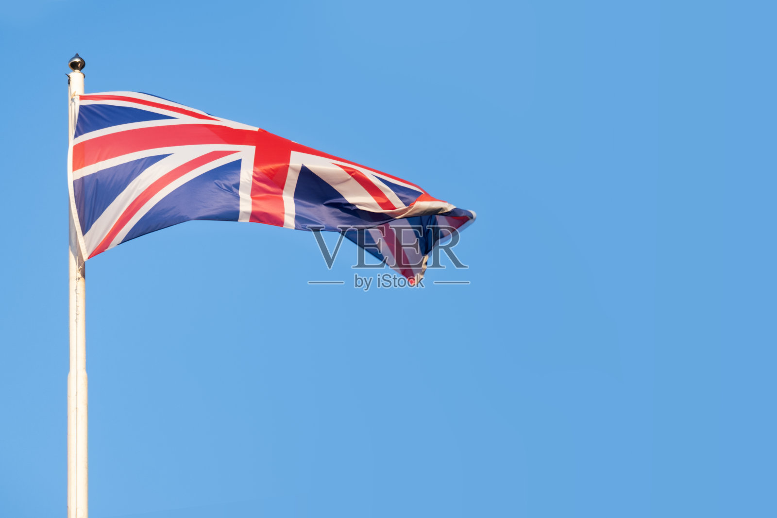 英国国旗在蓝天的映衬下高高飘扬，象征着英国的传统、坚韧和坚定不移的精神照片摄影图片