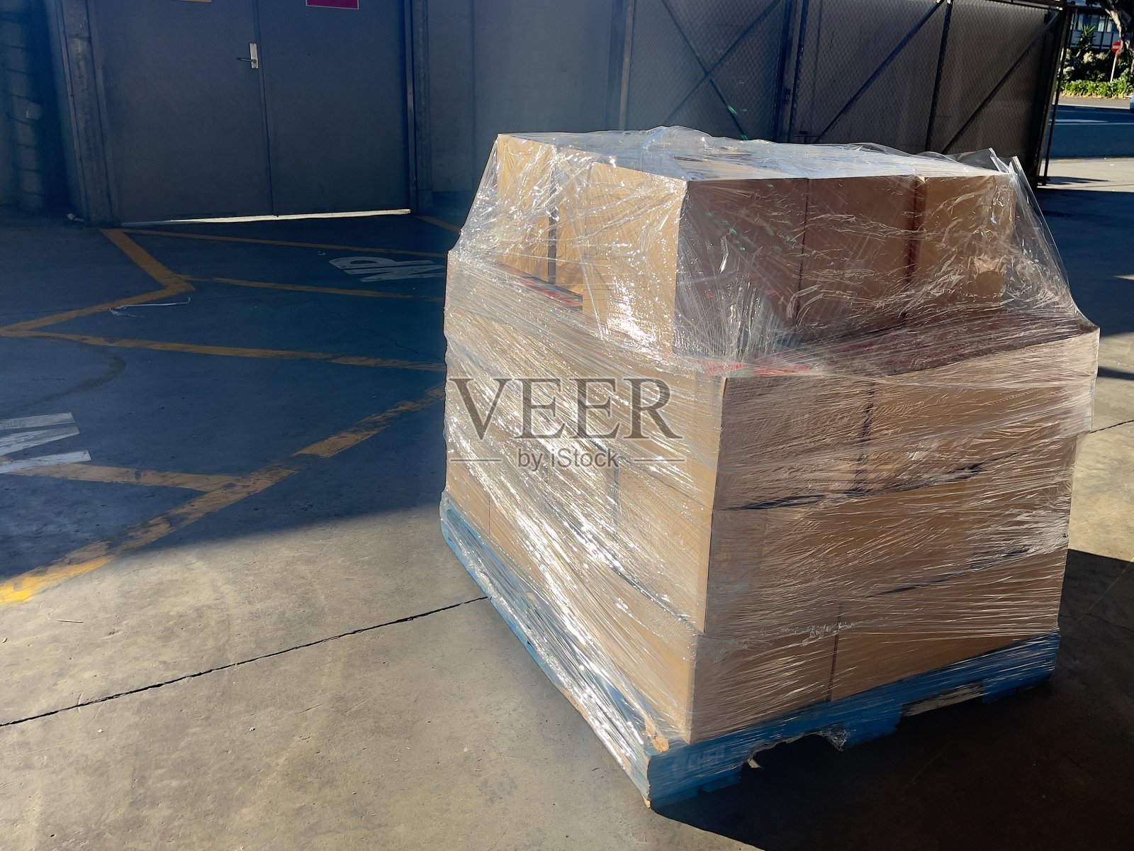 仓库里的纸箱装在蓝色的托盘上，用保鲜膜包裹着照片摄影图片