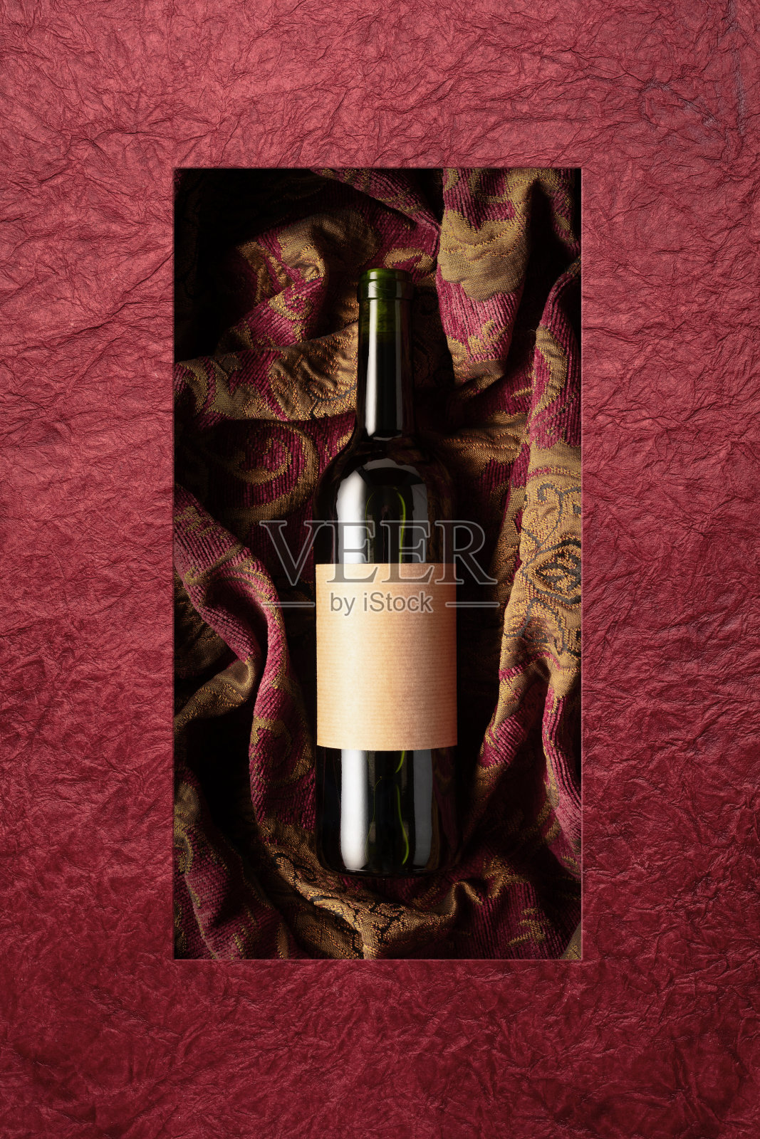 一瓶红酒在一个复古挂毯与深红色和金色的花卉装饰。照片摄影图片