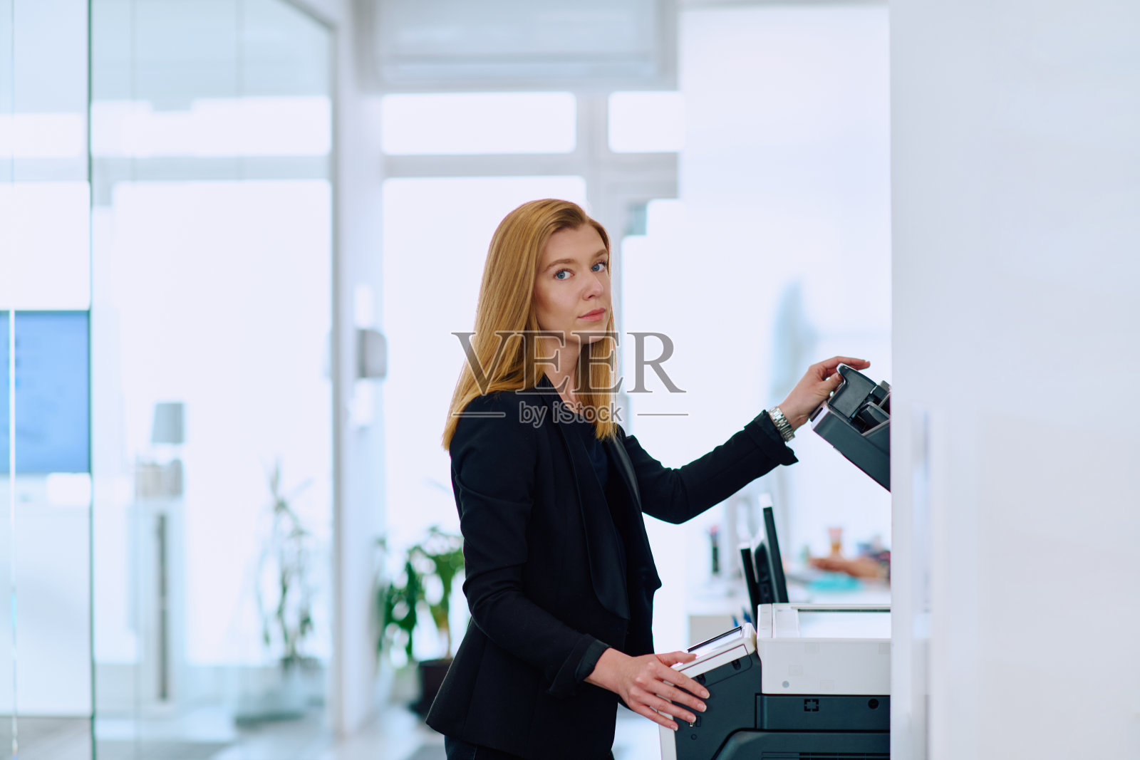 金发女商人在办公室使用打印机。照片摄影图片