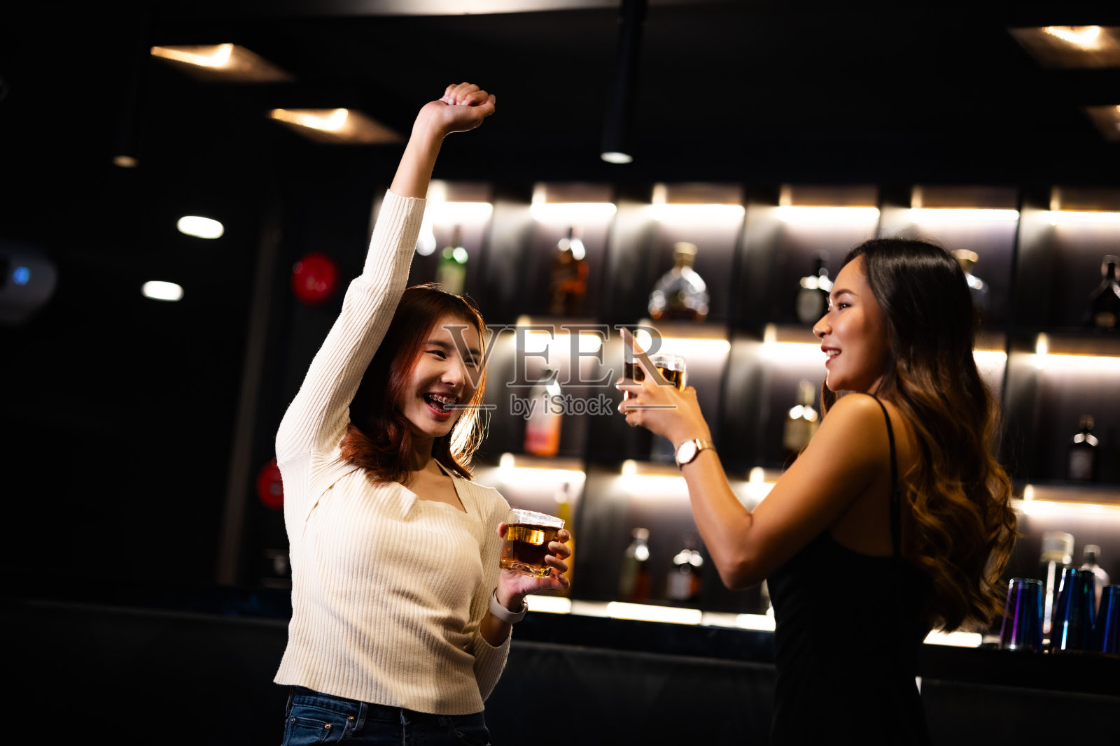 两个女人在夜总会喝酒，聊天，聚会，一起快乐地跳舞。照片摄影图片