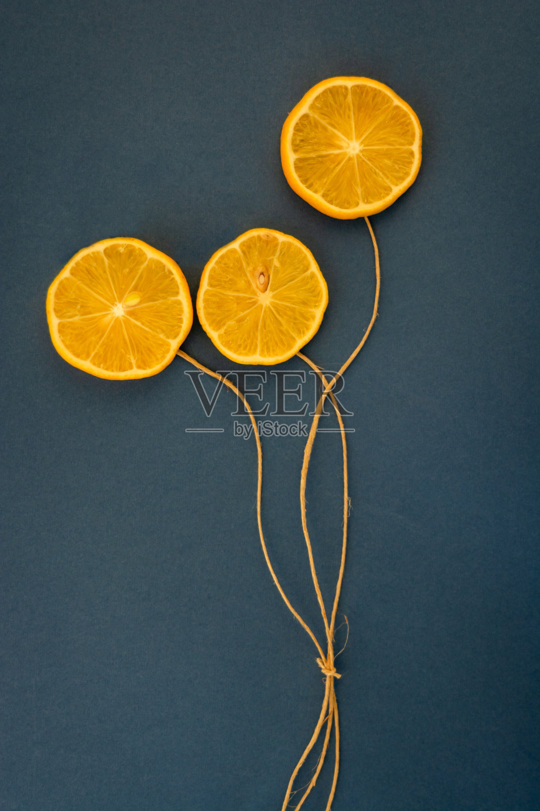 蓝色背景上系着绳子的柠檬照片摄影图片