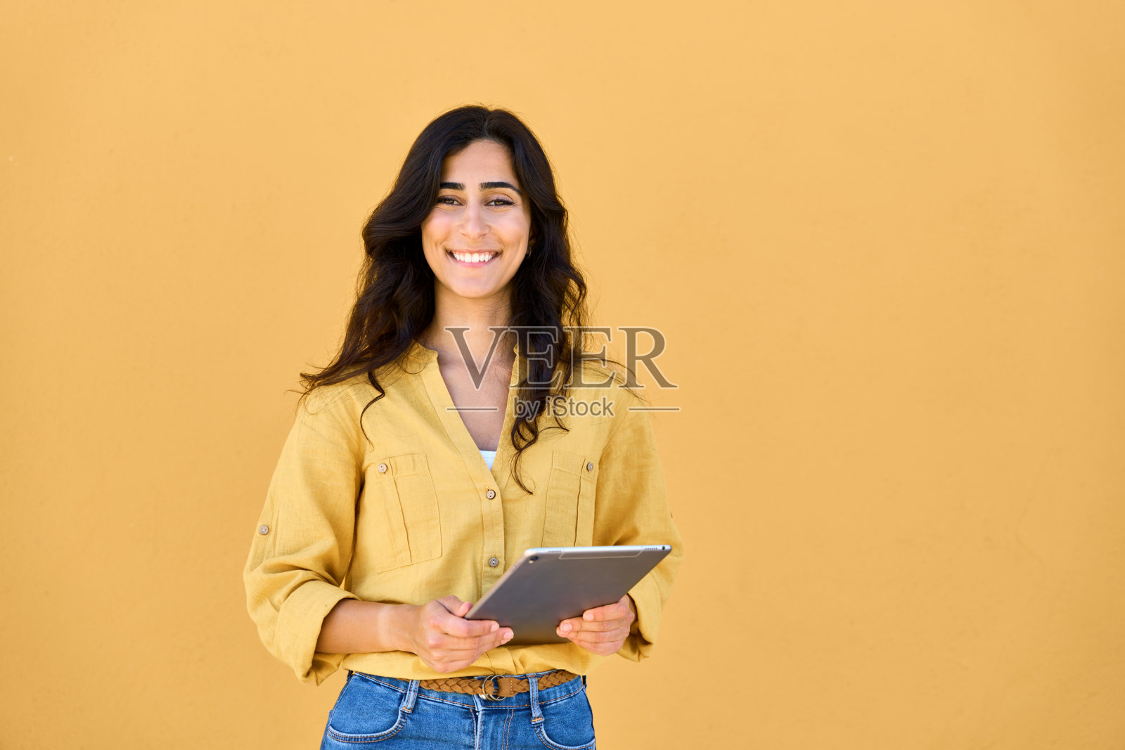 中东黑发女学生，在平板电脑上使用网络应用程序在线学习，学习，交流。年轻女子的肖像拿着数字pad电脑孤立照片摄影图片