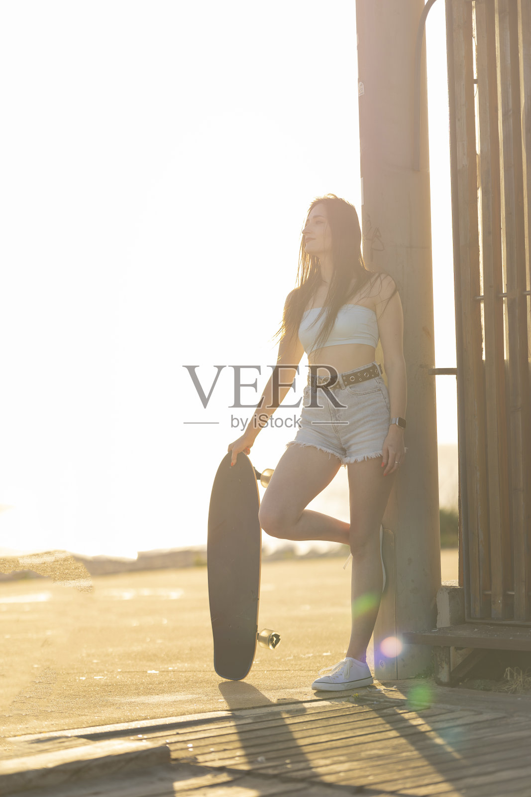 一个女人拿着滑板站在人行道上照片摄影图片