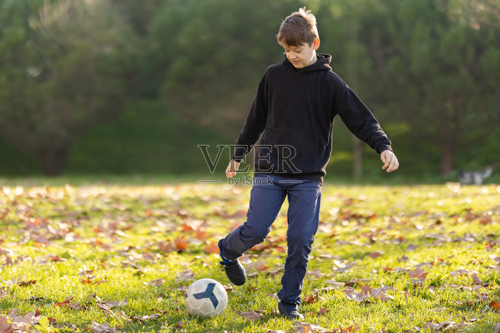 一个男孩在公园里踢足球照片摄影图片