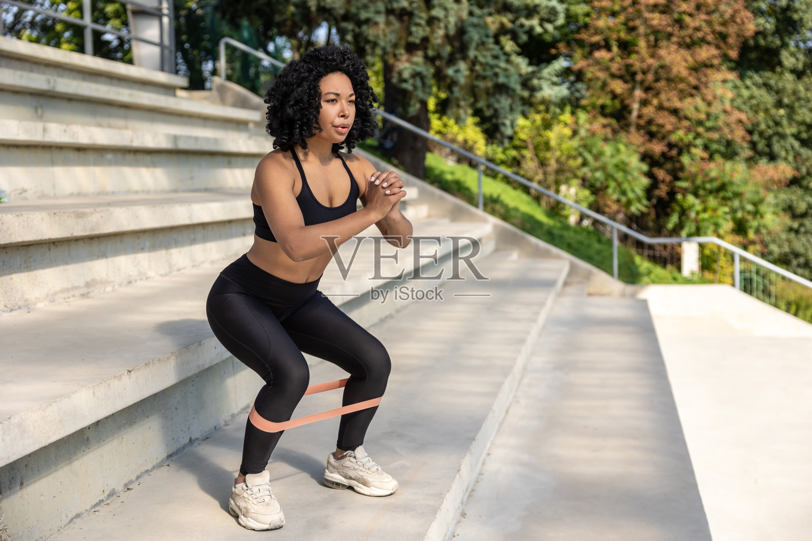 穿黑色上衣的黑发女人在锻炼力量带和深蹲照片摄影图片