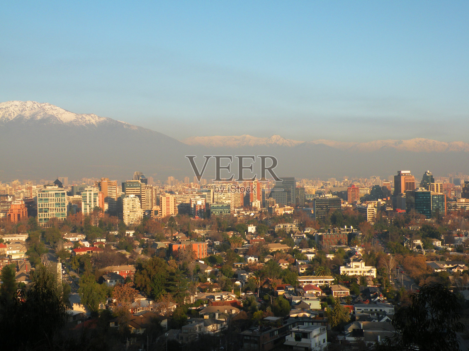 夕阳下普罗维登西亚的建筑物，背景是雪山和空气污染照片摄影图片