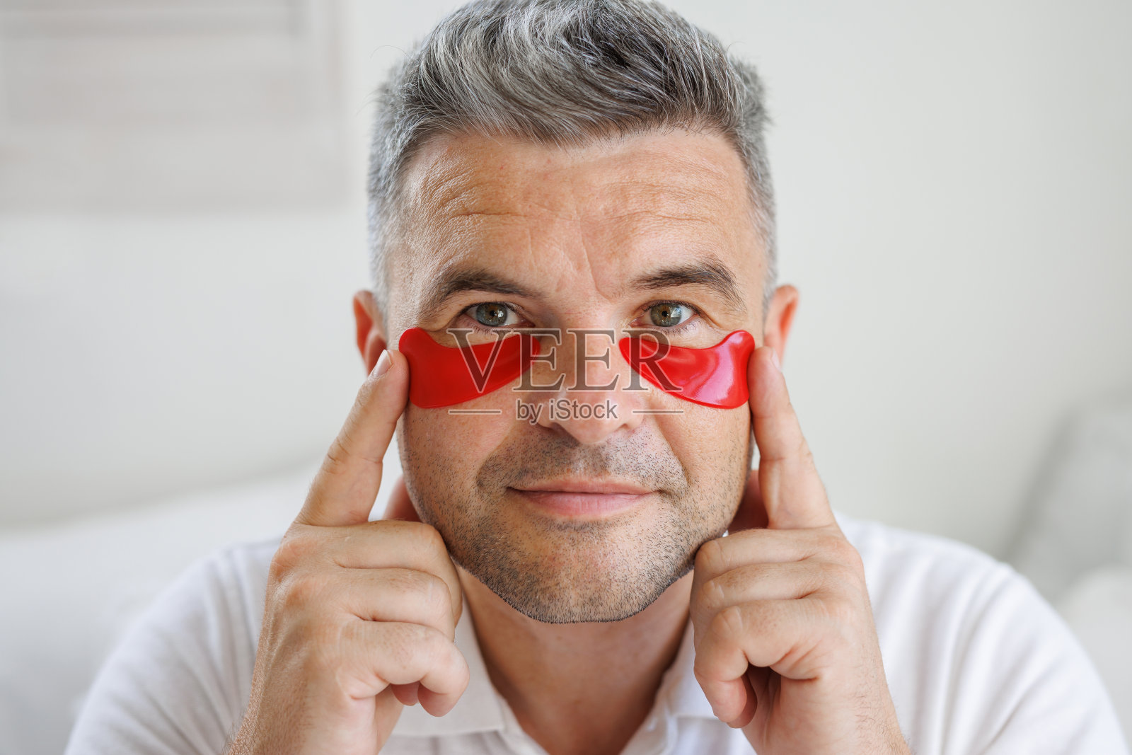 一名男子在他的眼睛下面涂抹含有维生素的保湿贴片照片摄影图片