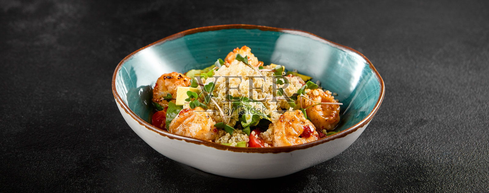 虾和藜麦沙拉，牛油果和西红柿，在一个绿松石碗照片摄影图片