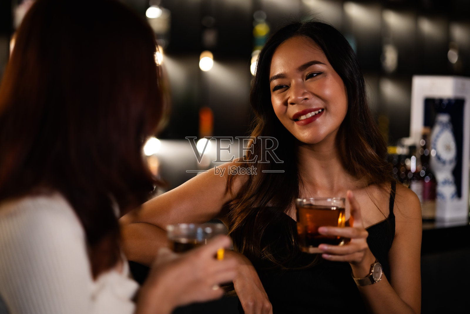 两个女人在夜总会喝酒，聊天，聚会，一起快乐地跳舞。照片摄影图片