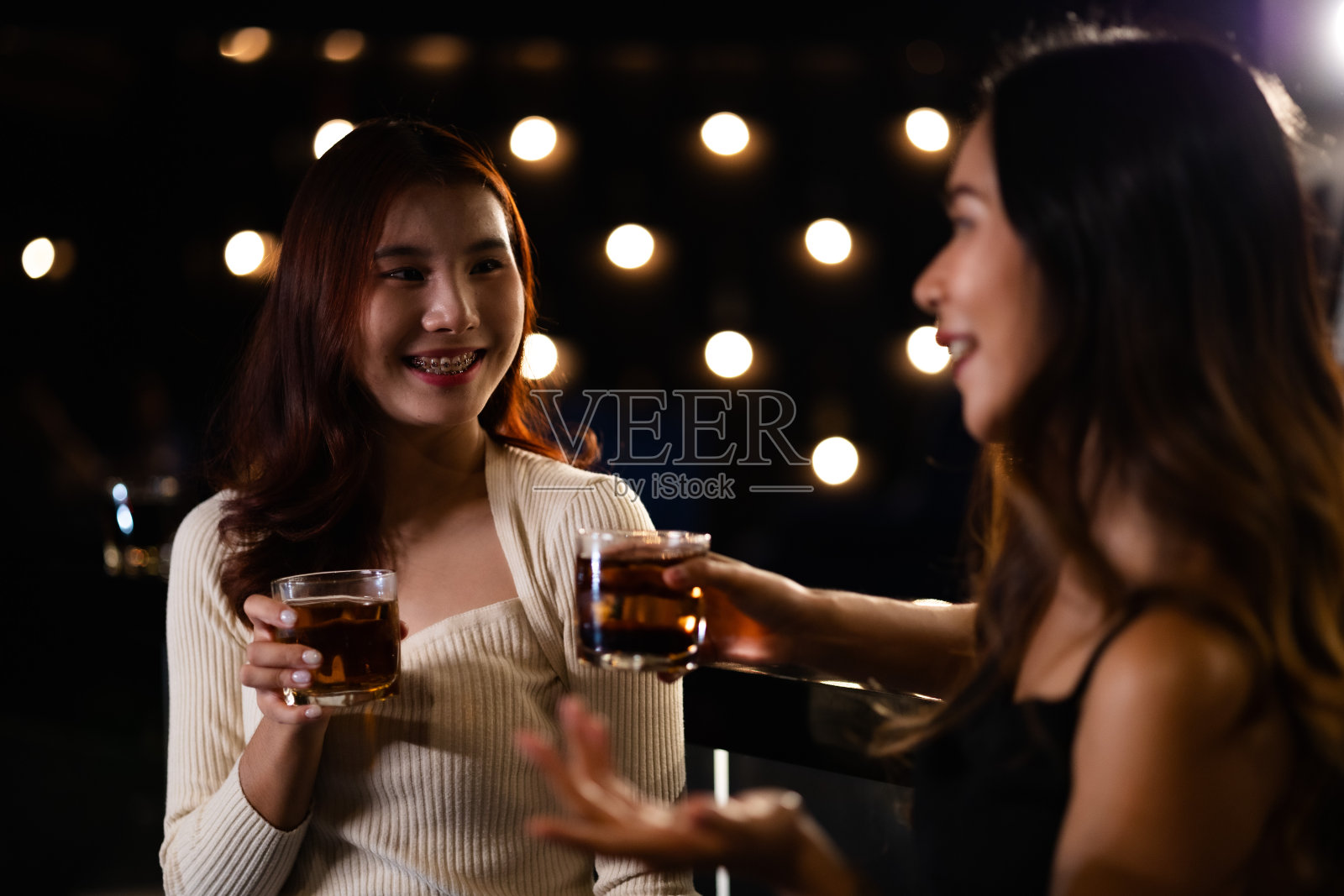 两个女人在夜总会喝酒，聊天，聚会，一起快乐地跳舞。照片摄影图片