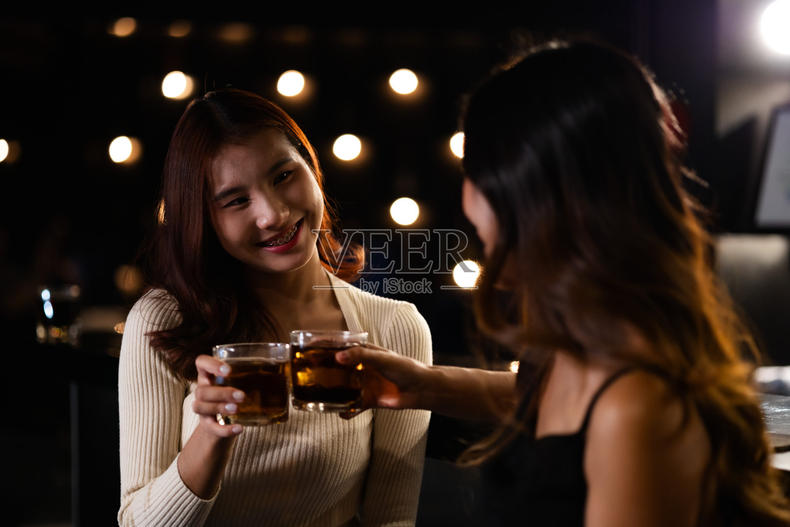 两个女人在夜总会喝酒，聊天，聚会，一起快乐地跳舞。照片摄影图片