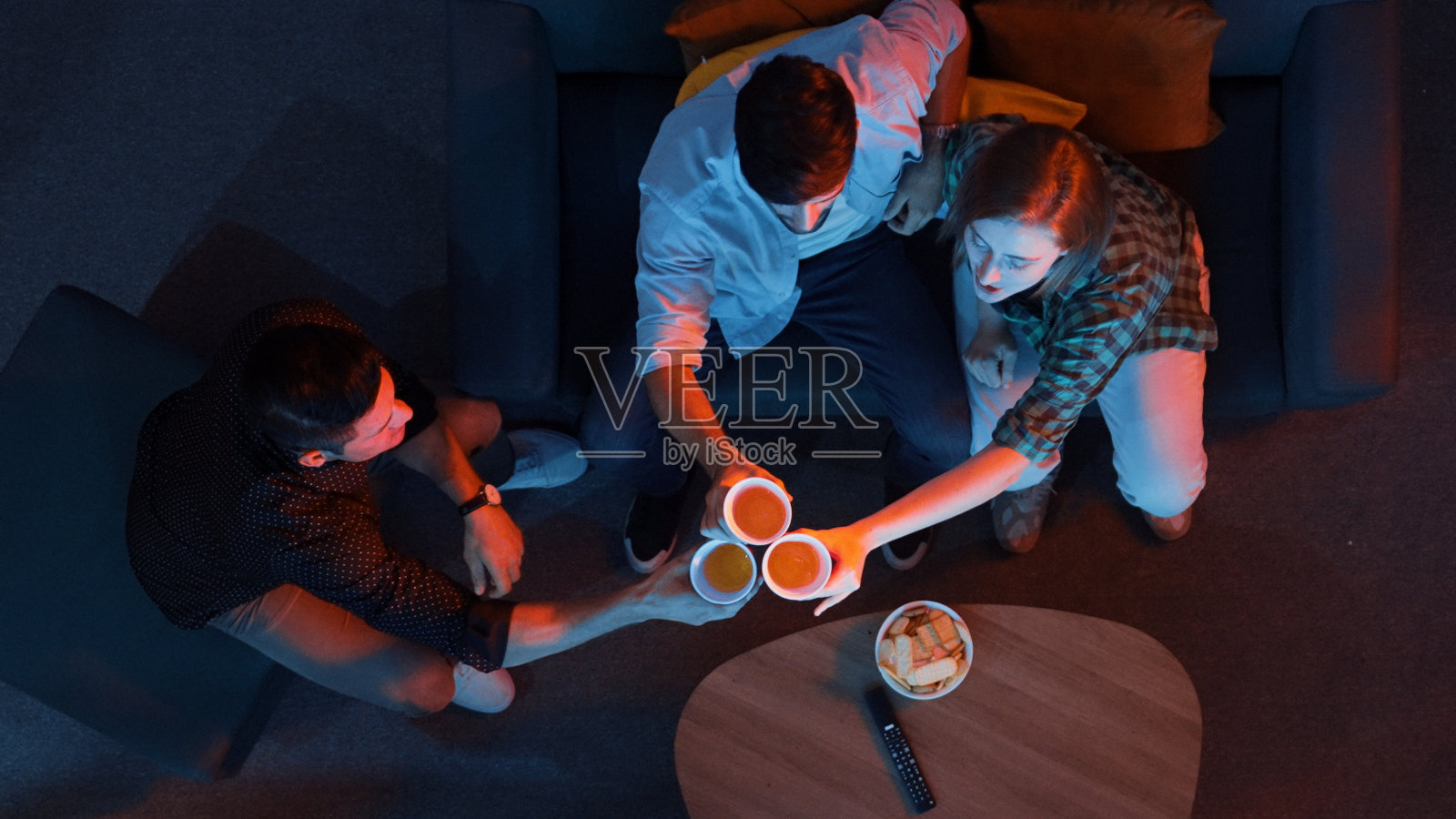 家人和同事坐在客厅里为球队加油。召开。照片摄影图片