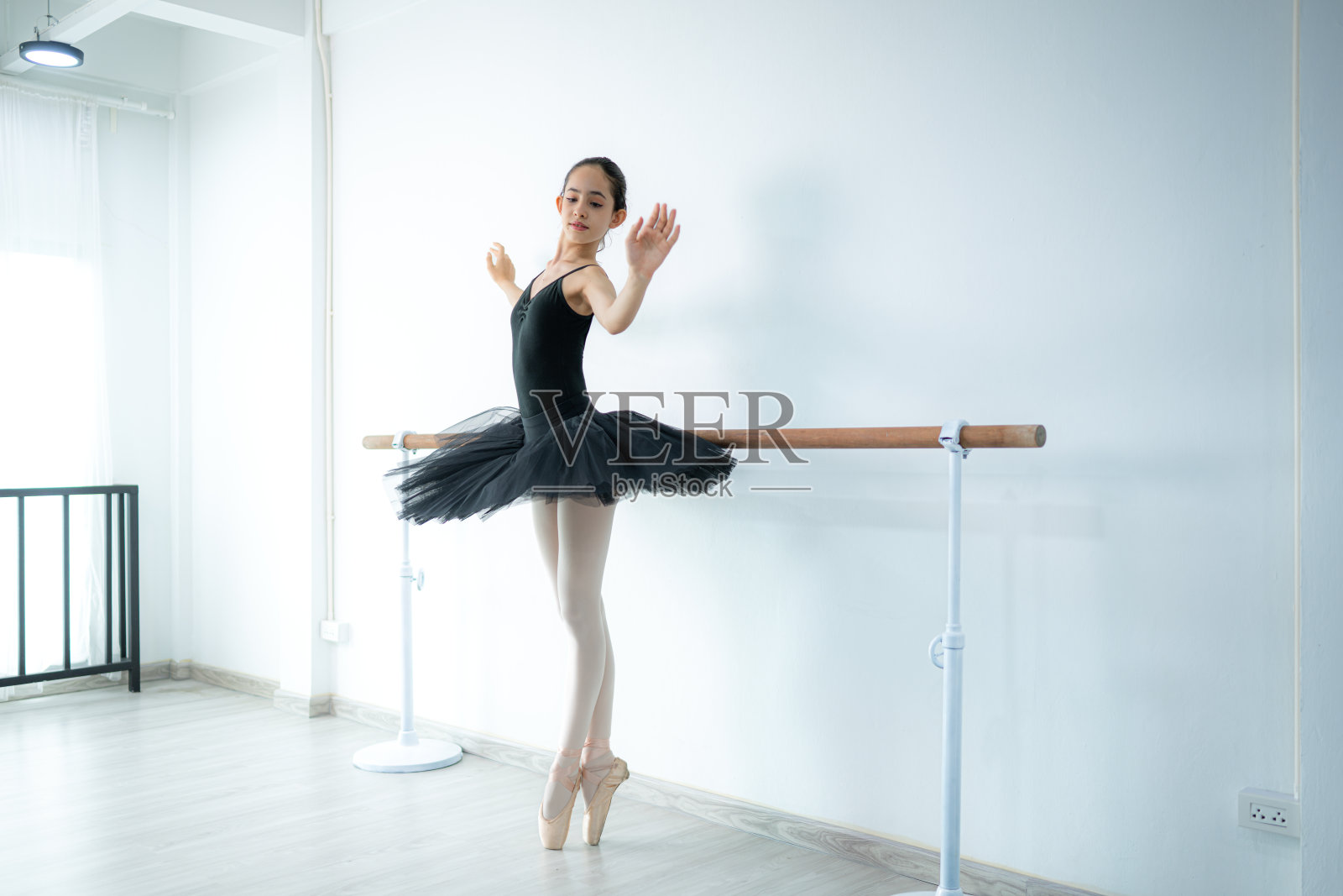 一个芭蕾舞女学生在家里练习芭蕾舞，背景是白色的照片摄影图片