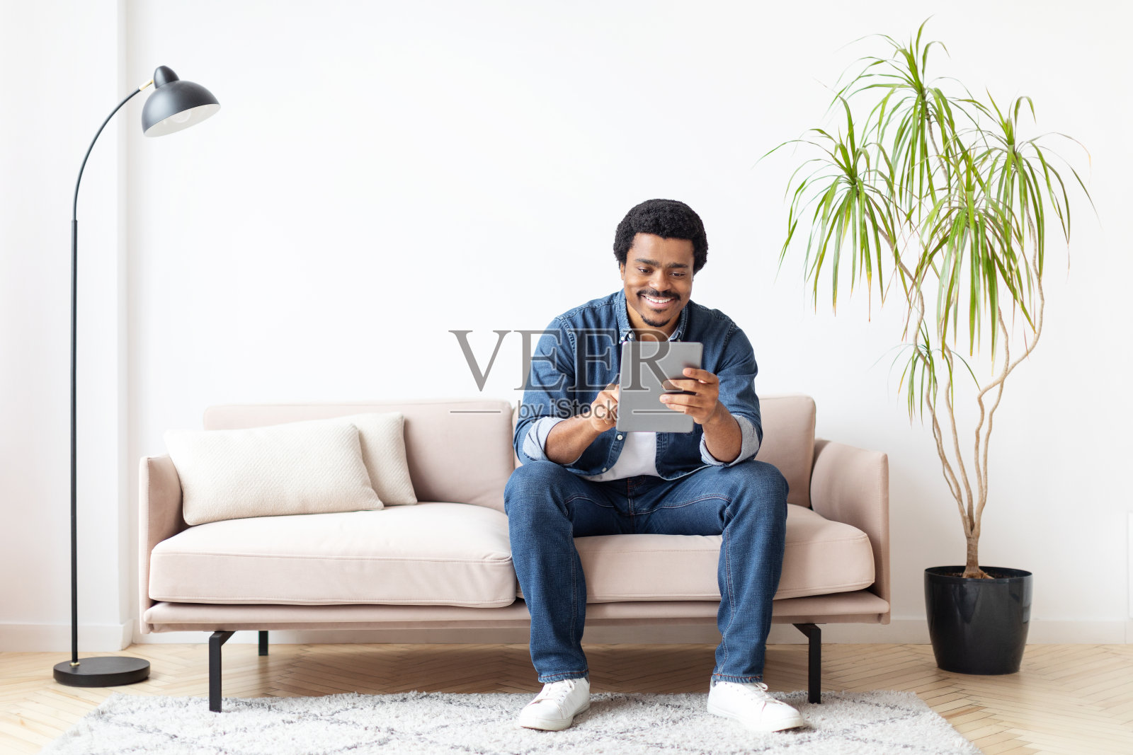 一名男子坐在沙发上使用平板电脑照片摄影图片