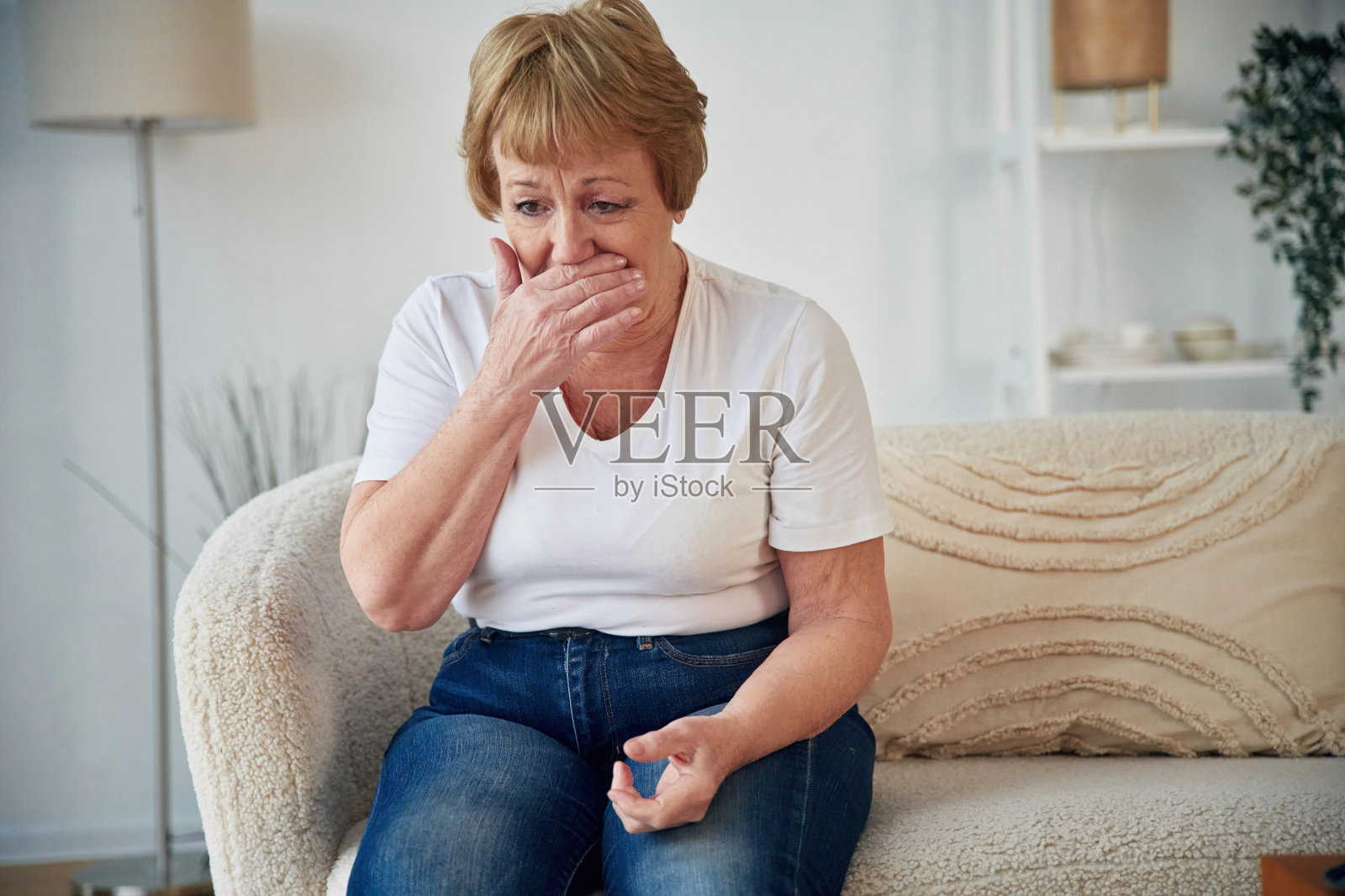 咳嗽。感觉病了。一位年长的妇女在家里的客厅里照片摄影图片