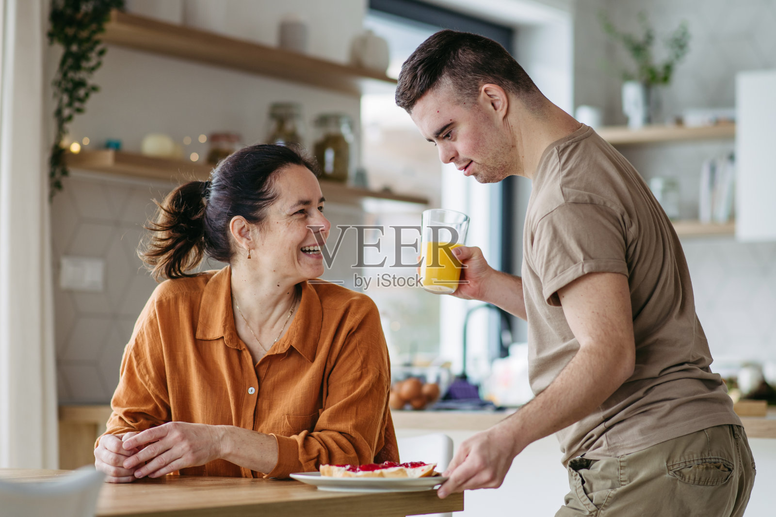 患有唐氏综合征的年轻男人为母亲准备母亲节早餐照片摄影图片