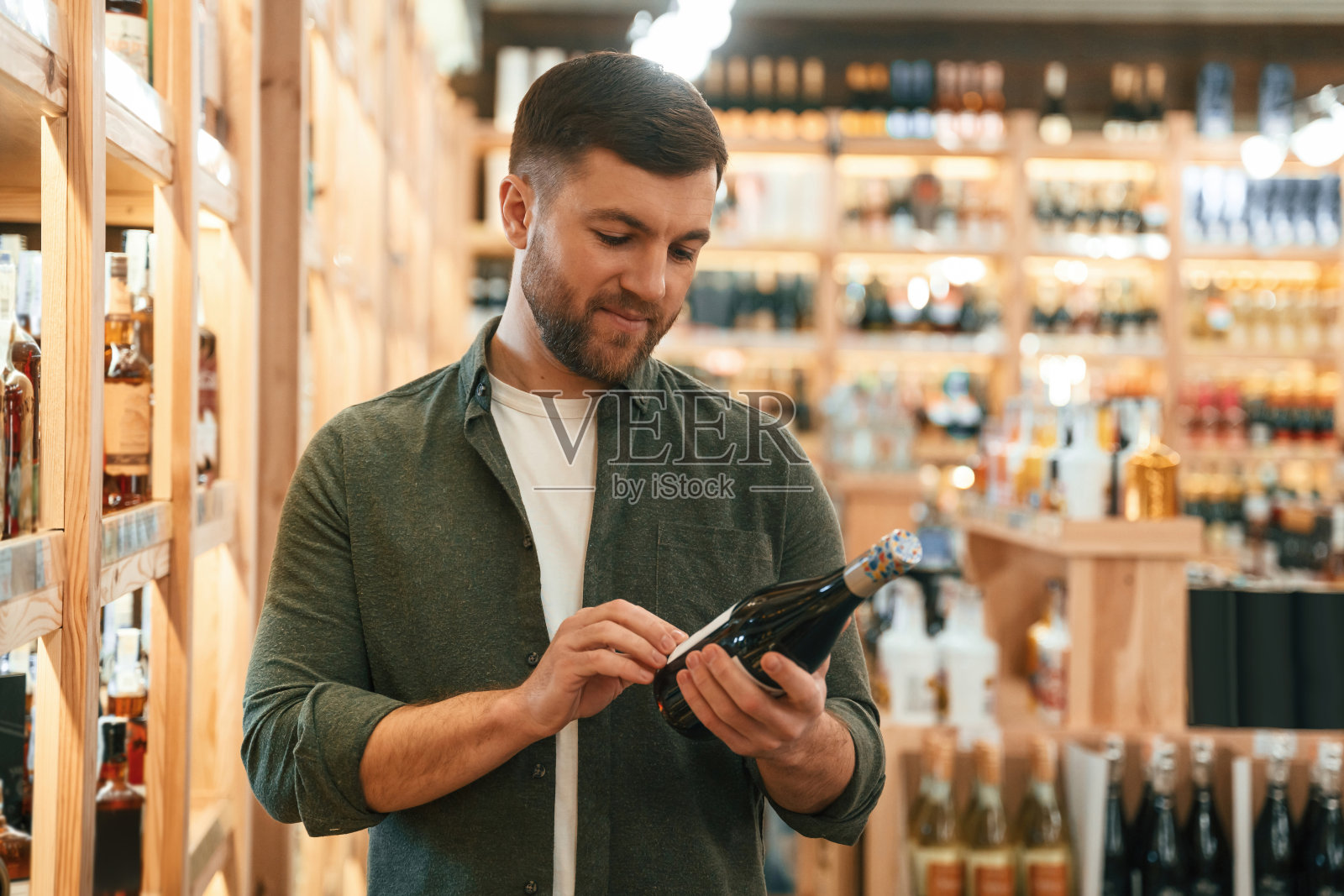 顾客正在看瓶子。一个人正在店里挑选葡萄酒照片摄影图片