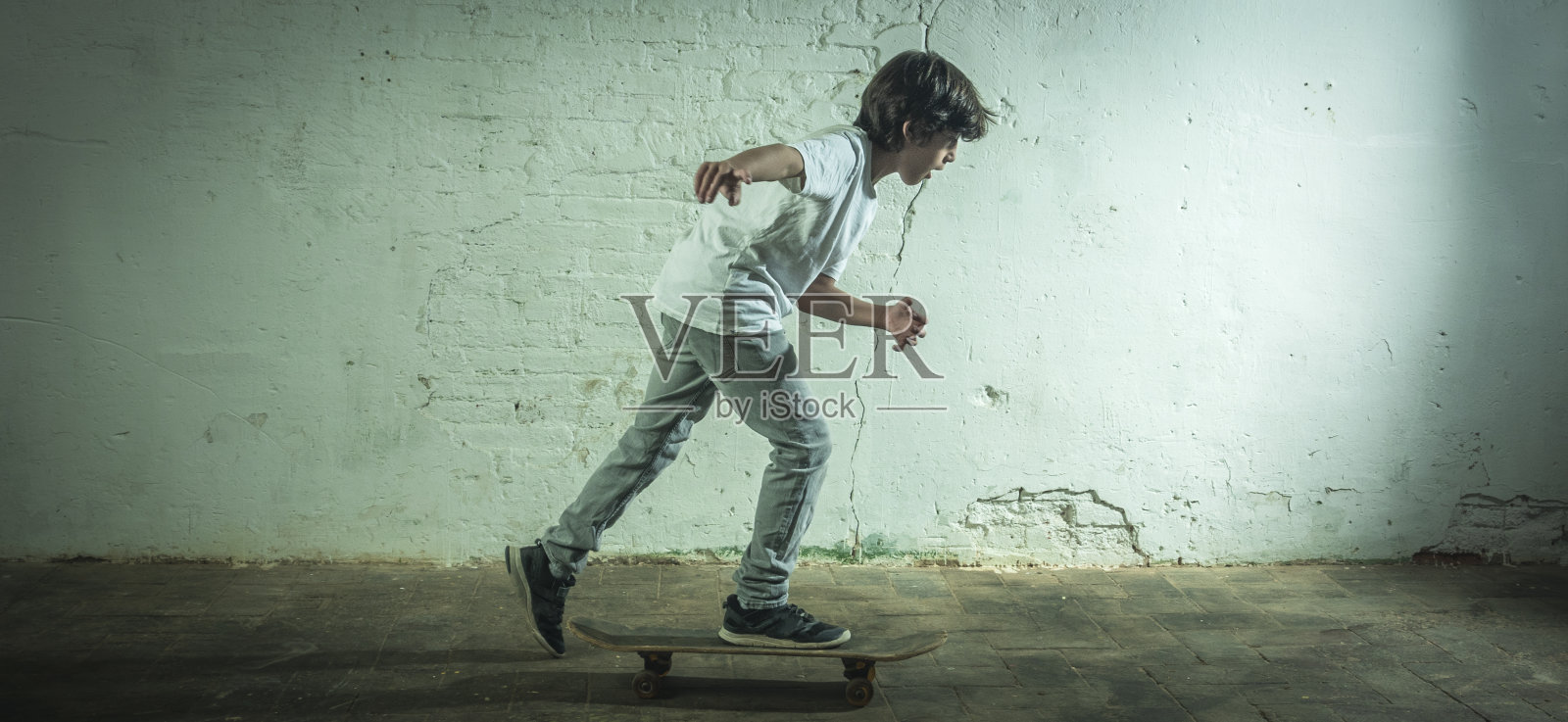 一个男孩带着滑板在工业环境中移动。照片摄影图片