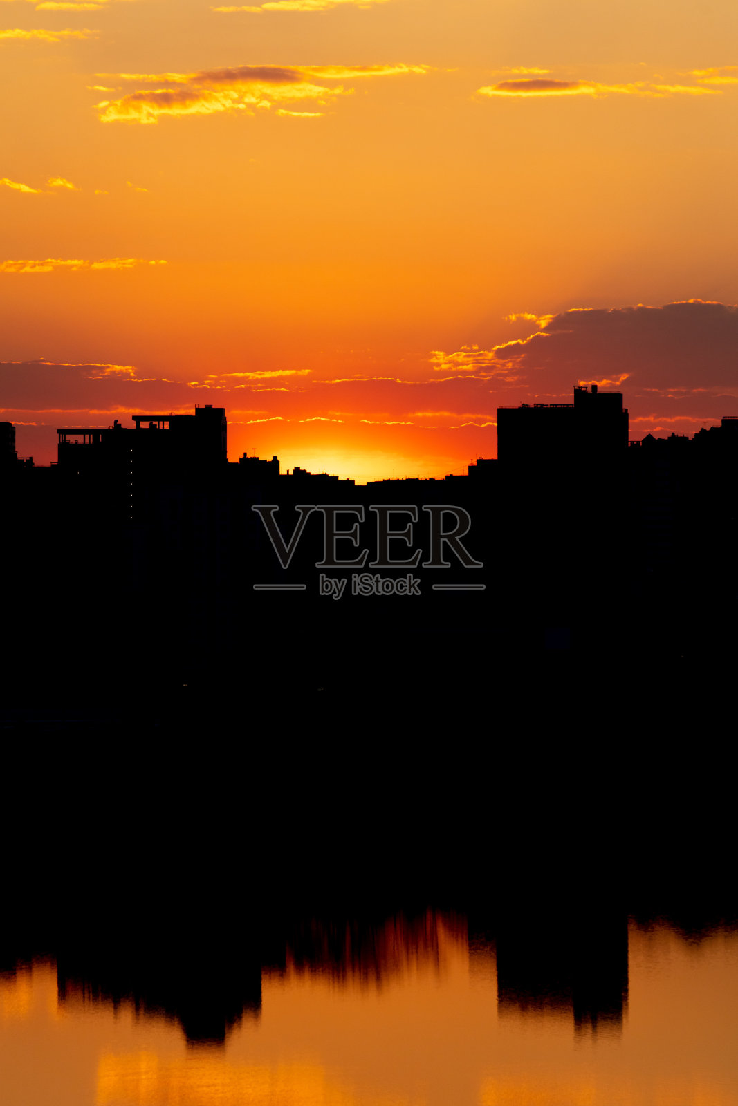 日落时城市的剪影映在水面上照片摄影图片