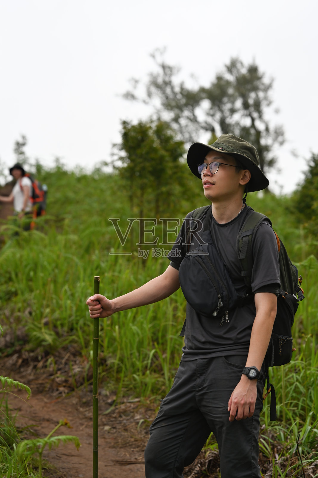 年轻的亚洲男性徒步旅行者背着背包和他的朋友在热带山上徒步旅行的特写图像照片摄影图片