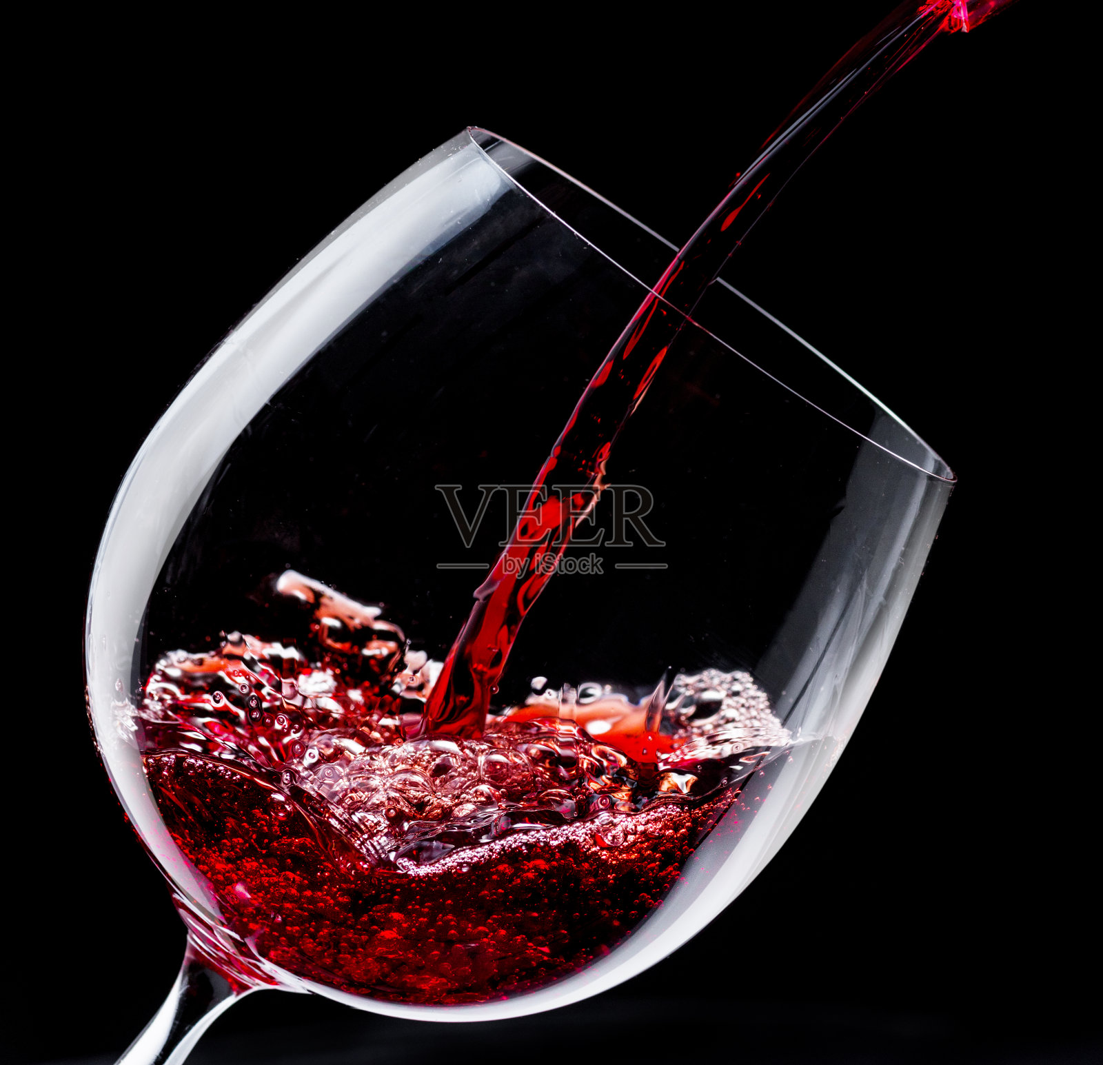 在黑色背景下将红酒倒入酒杯。照片摄影图片