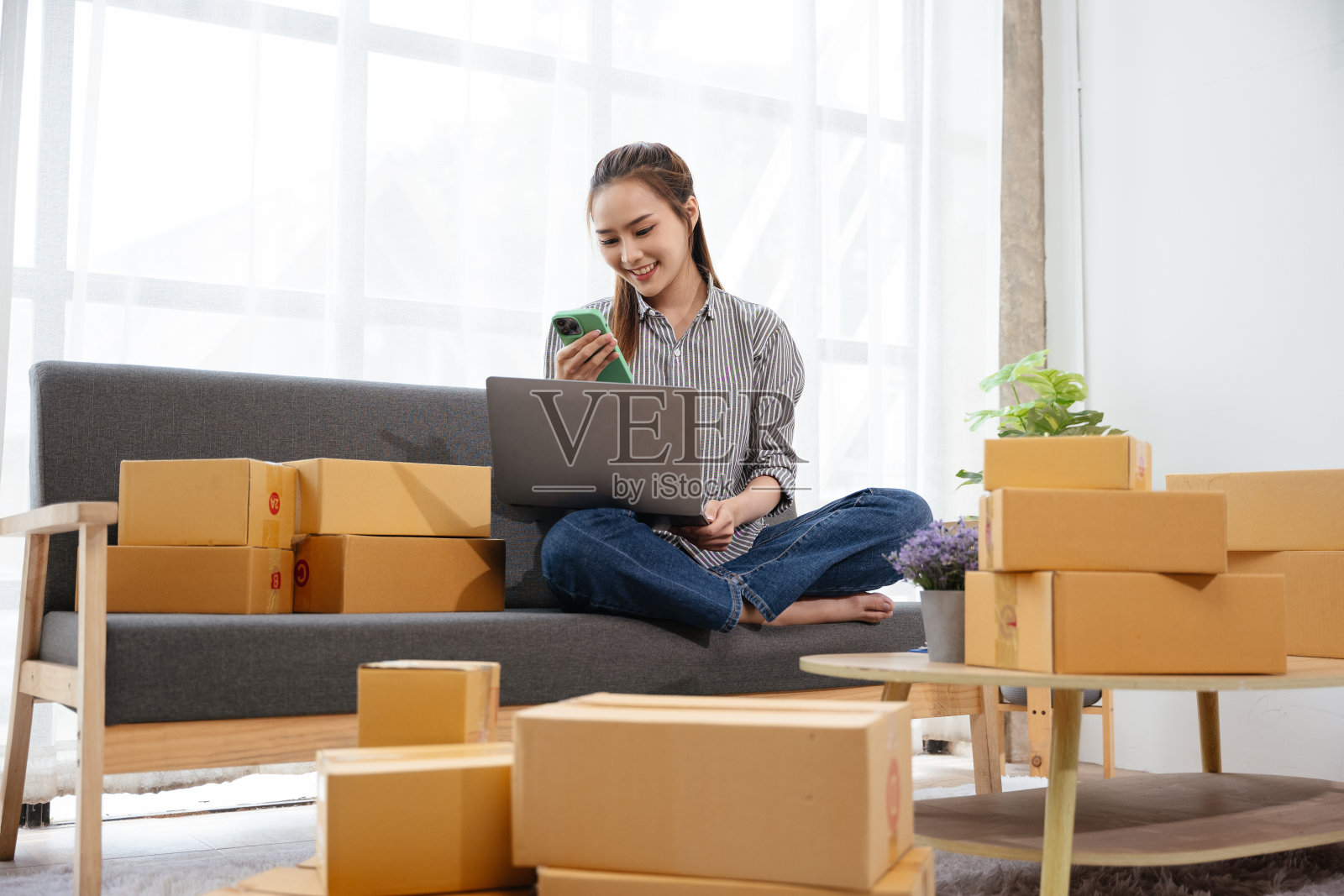 业主是中小企业的一名妇女，她通过电话和笔记本电脑接到客户的订单，然后在家里用纸板箱包装好产品，准备交付给客户照片摄影图片