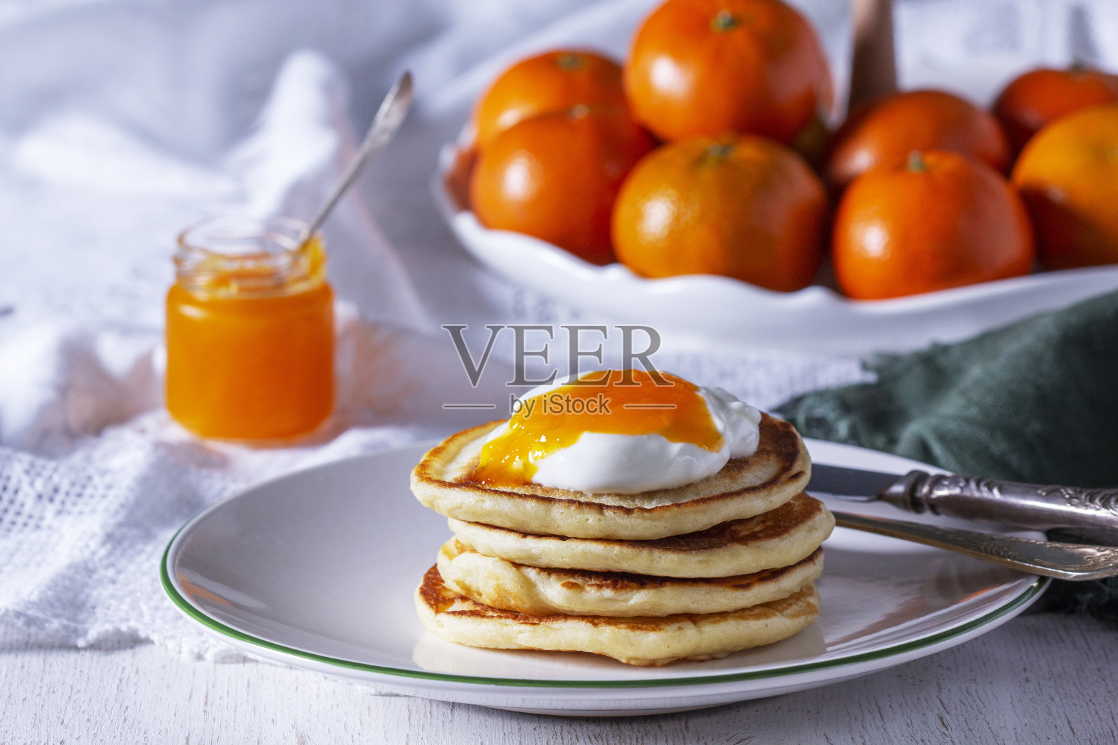 薄煎饼配上橘子果酱和酸奶油，还有淡色背景的橘子。照片摄影图片