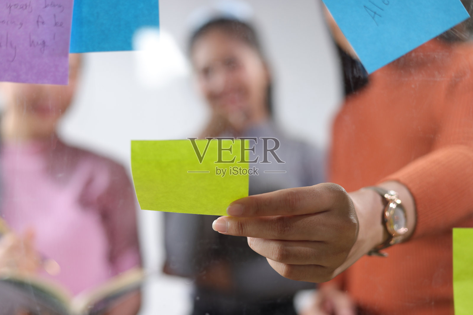 创业会议，同事们在办公室的透明板和纸贴纸上讨论商业项目计划。一群想与同事进行头脑风暴和分享想法的女性。照片摄影图片